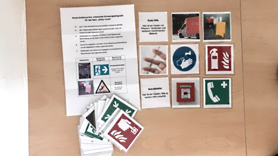 Bild verschiedener Karten mit Symbolen und einer Spieleanleitung der "Safety Cards"