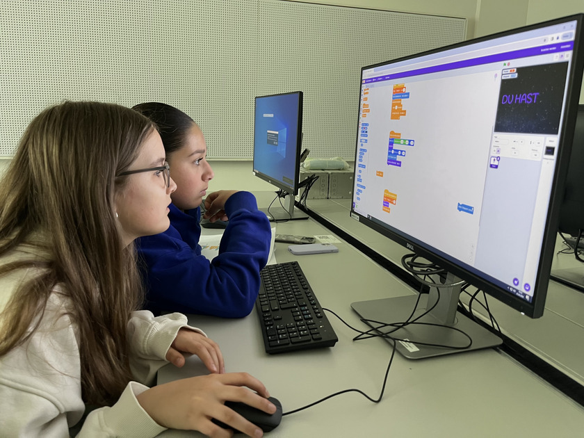 Zwei Schülerinnen sitzen vor einem Computer.