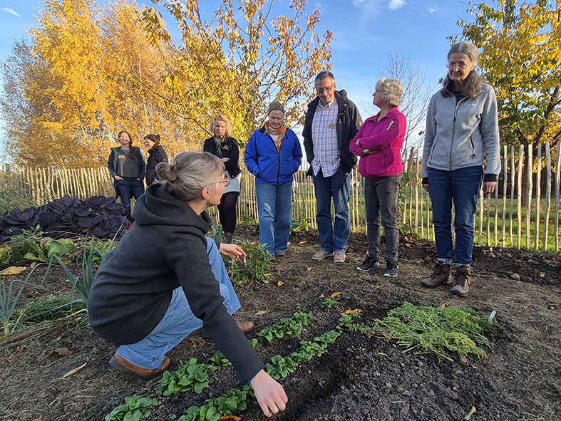 Eine Gruppe von Personen steht im Garten am WABE-Zentrum, dem Versuchsbetrieb der Ökotrophologie