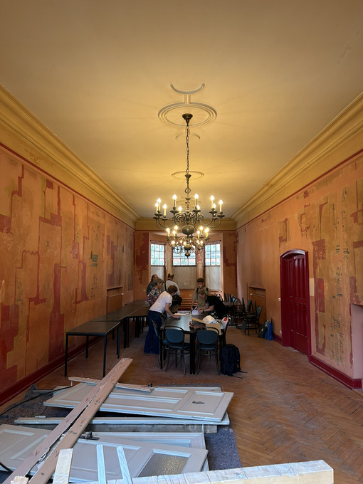 Blick in den Festsaal. Zusehen sind die Kronleuchter und zum Teil freigelegte Zeichnungen an den hohen Wänden. 