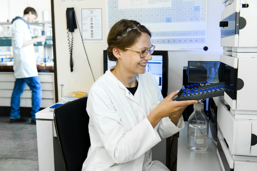 Eva Berghaus sitzt in einem Labor am Hochleistungsflüssigkeitschromatografen.