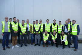 Die Workshop-TeilnehmerInnen sitzen bzw. hocken vor der kürzlich neu erbauten Lagerhalle der Nosta Logistics GmbH am Standort Ladbergen.