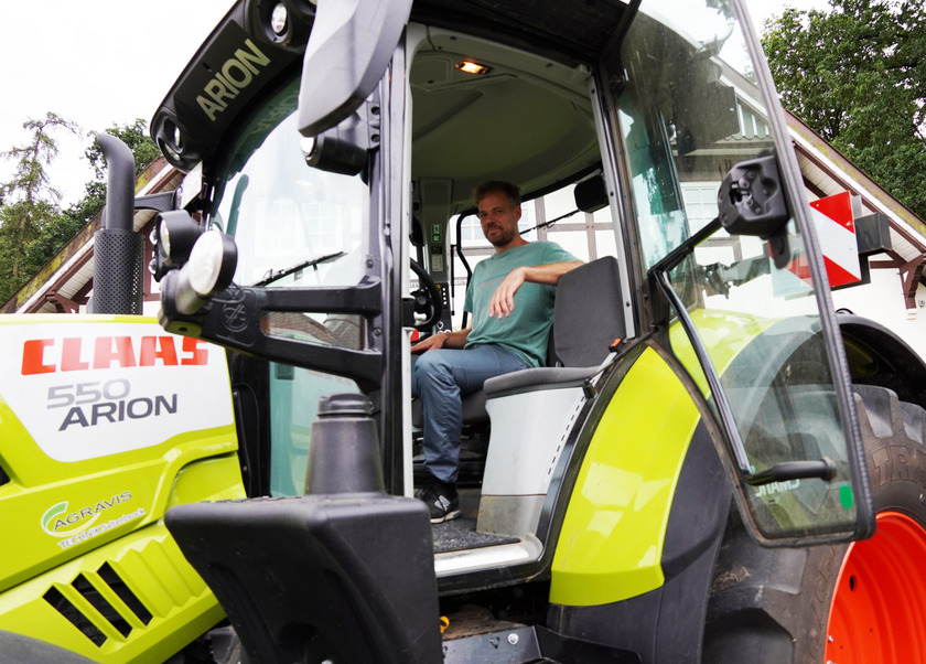 Waldhof-Mitarbeiter Tobias Kamps sitzt in der Fahrerkabine eines Traktors.