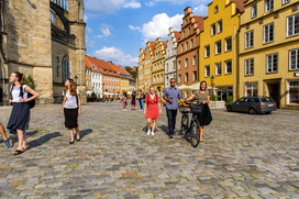 Studierende gehen durch die Altstadt von Osnabrück und schauen sich Gebäude an.