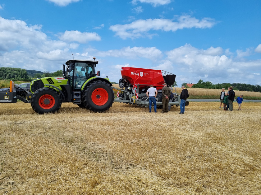 Eine Traktor mit Anhänger fährt über einen Acker.