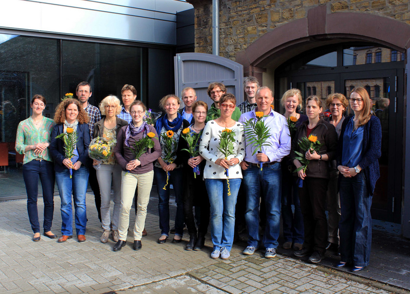 WIMHOS-Gruppenbild Das Bild zeigt eine Gruppe von Menschen mit Sonnenblumen in der Hand.
