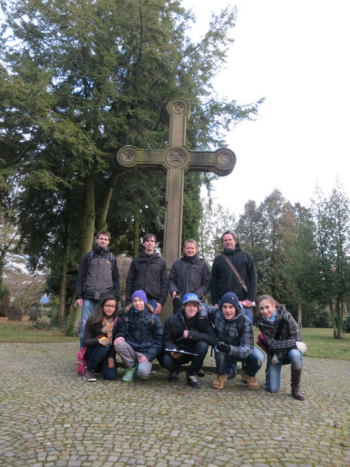 Auf dem Bild sieht man eine Gruppe von neun Personen vor einem großen Kreuz.