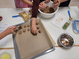 Kinderhände formen Kartoffelbällchen und legen sie auf ein Blech.