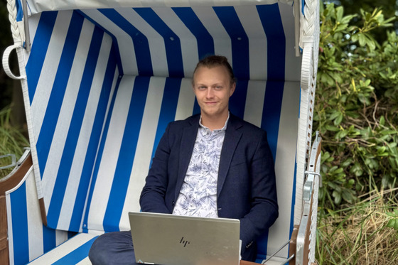 Der junge Gründer mit Laptop in einem Strandkörbe.