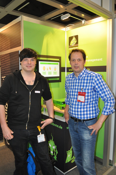 Das Bild zeigt zwei Männer vor einem grünen Messestand.