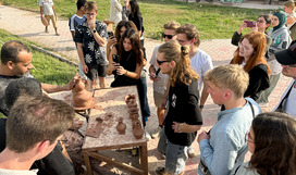 Studierende stehen einem Keramiker bei der Arbeit zu