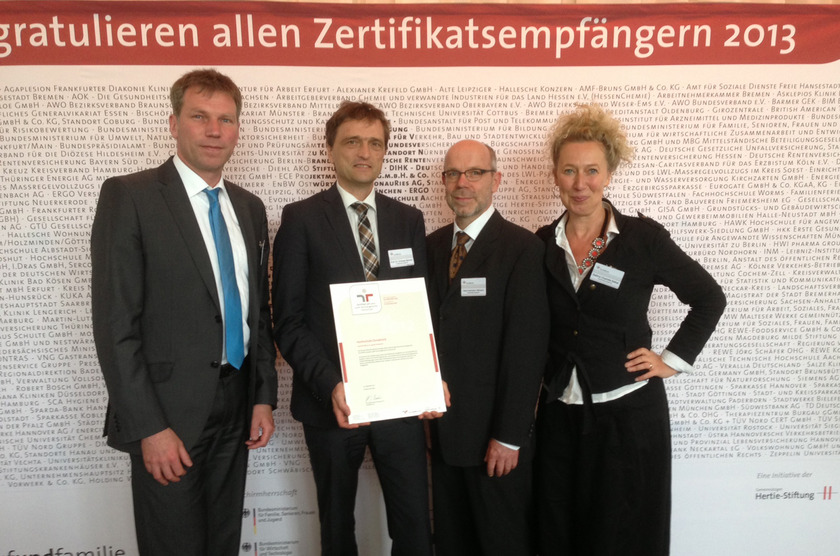 Auf dem Bild sieht man vier Personen, die eine Urkunde in der Hand halten.