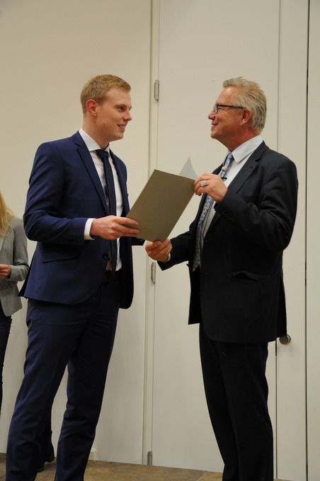 Prof. Dr. Bernd Lehmann überreicht einem Absolventen feierlich seine Abschlussurkunde