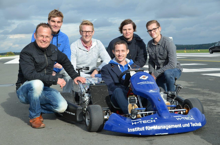 Das Bild zeigt Männer in und um ein Elektro-Kart.