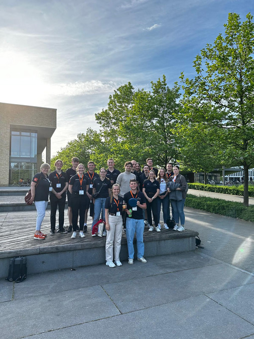 Gruppefoto, eine junge Frau und ein junger Mann stehen prominet im Vordergrund und halten eine Urkunde in die Kamera.