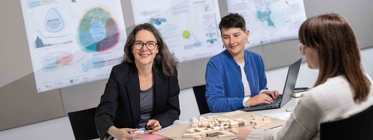 Professorin bespricht mit zwei Personen ein Stadt- und Landschaftsmodell.