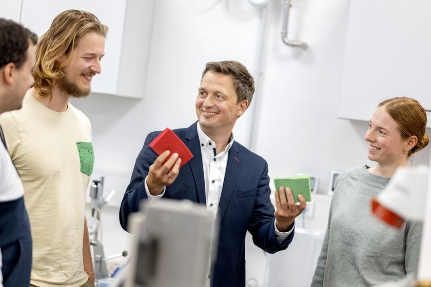 Vier menschen unterhalten sich. Einer von ihrnen hat Prototypen aus Kunststoff in der Hand.