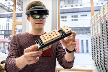 Student hat eine Augmented Reality Brille auf und betrachtet damit eine Legostein-Konstellation