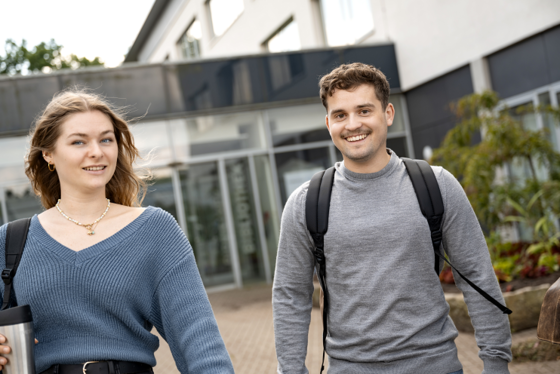 zwei Studierende gehen vom Hochschulgebäude weg