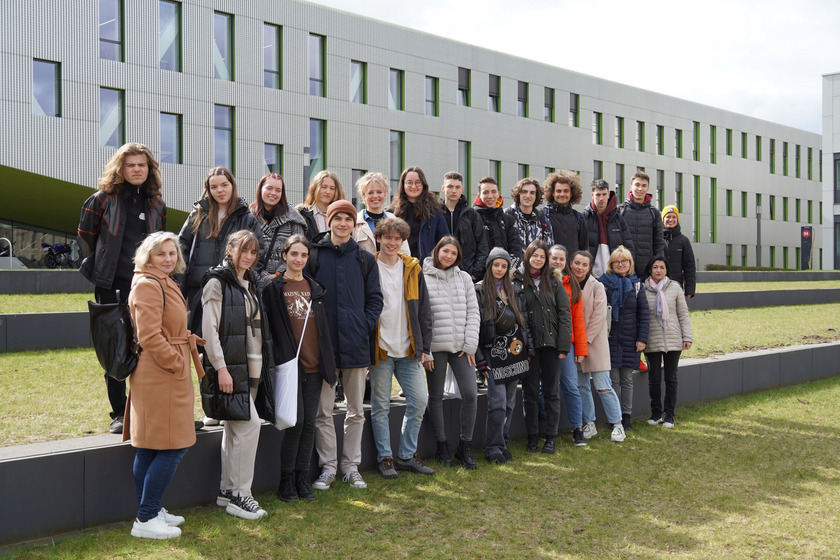 Gruppe junger Menschen posiert vor einem Gebäude der Hochschule