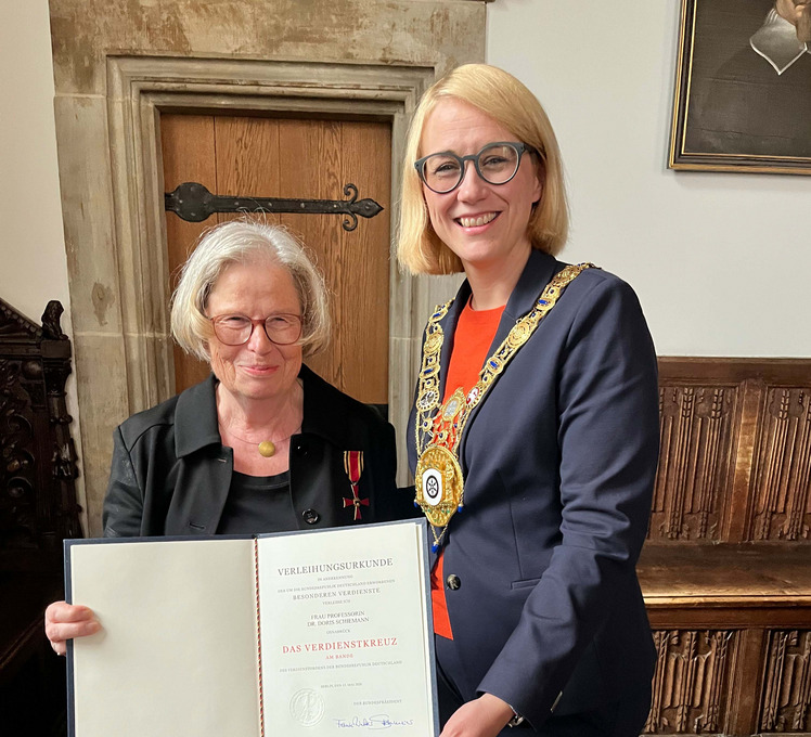 Das Bild zeigt die Ausgezeichnete mit dem angesteckten Bundesverdienstkreuz und der Urkunde in der Hand. Daneben steht die Oberbürgermeisterin.