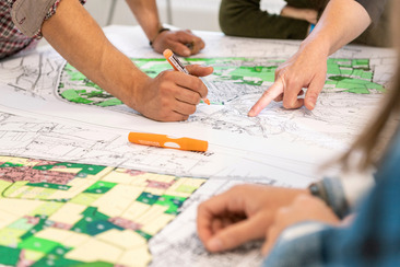Ein Zeichentisch mit mehreren Personen, die mit Stift und Papier daran arbeiten