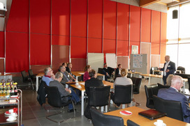 Projektleiter Prof. Franz stellt das Projekt KlimaLogis vor, die Teilnehmenden sitzen an verschiedenen Tischen und hören zu im Sitzungssaal des Rathauses in Bramsche 