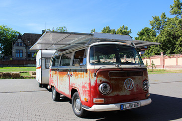 Der rote Solar-Bulli mit angehängtem Wohnwagen
