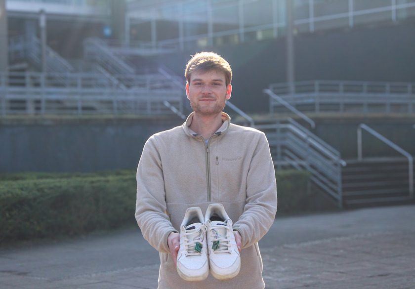 Junger Mann hält Schuhe mit Prototyp der Einlegesohlen in die Kamera.