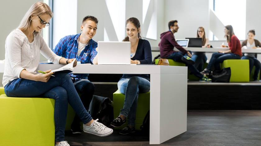 Lernlandschaft Man sieht Studierende in einem modernen Gebäude in einer Lerngruppe.