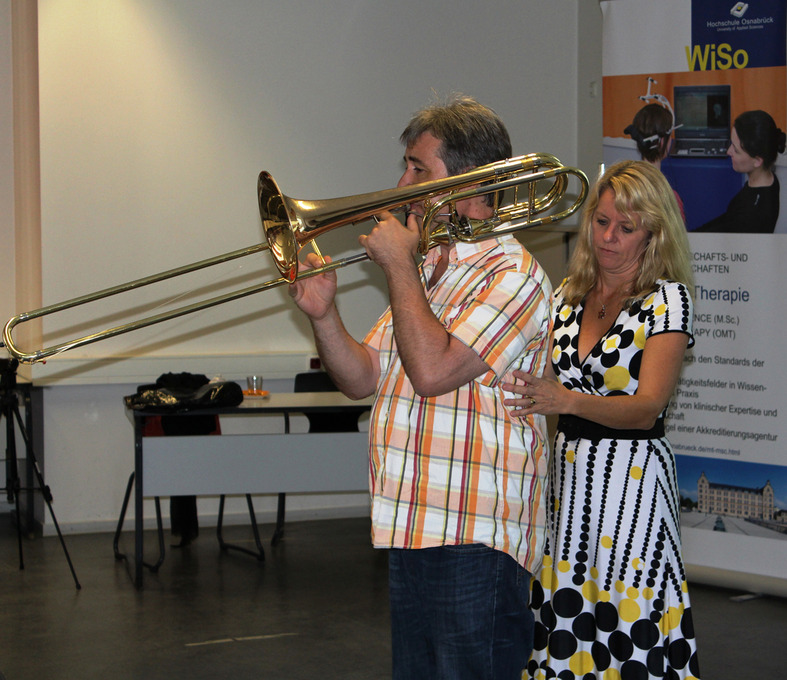 Das Bild zeigt einen Trompeter, hinter dem eine Frau steht.