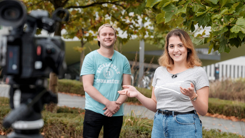 Die Campusreporter der Hochschule Osnabrück stehen vor einem Baum, während sie von einer Videokamera gefilmt werden.