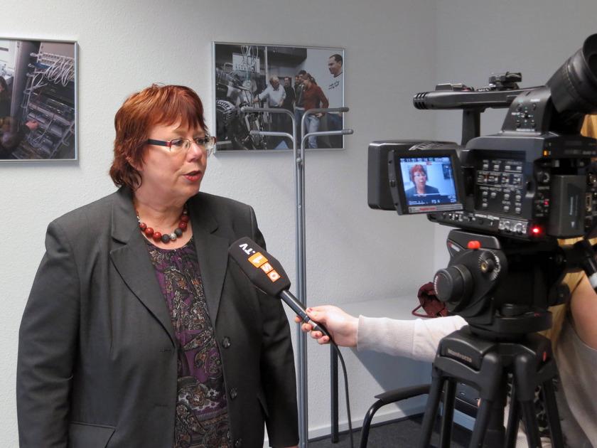Eine Frau mit roten kurzen Haaren gibt vor laufender Kamera ein Interview.