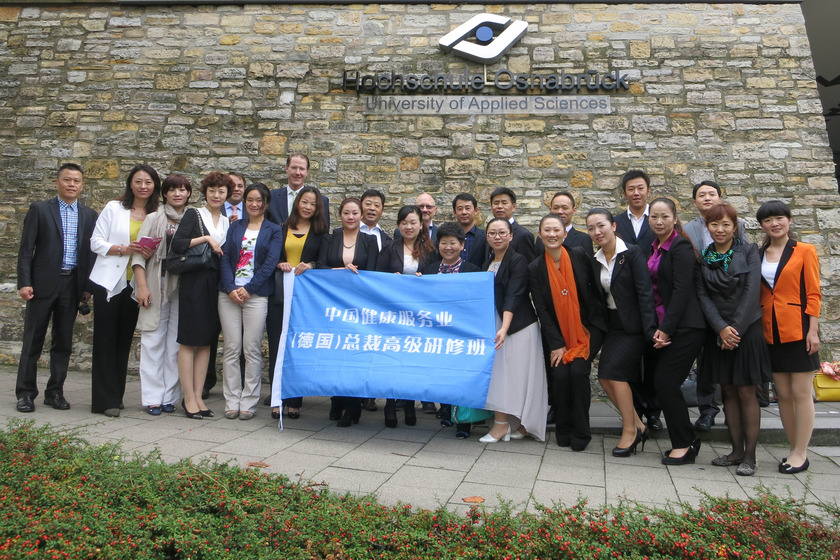 Man sieht eine Gruppe von 20 Chinesen mit einem blauen Plakat.