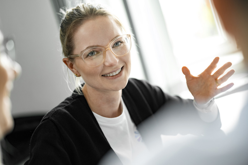 Eine Studentin gestikuliert und scheint sich mit anderen Studierenden zu unterhalten.