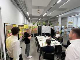 Abschlussrunde der Teilnehmenden des Workshops, in dem die Ergebnisse auf den Whiteboards präsentiert werden.