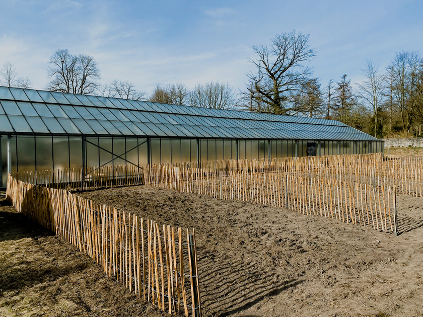 Das Gewächshaus von The Greenhouse mit davorliegenden abgesteckten Gartenabschnitten 