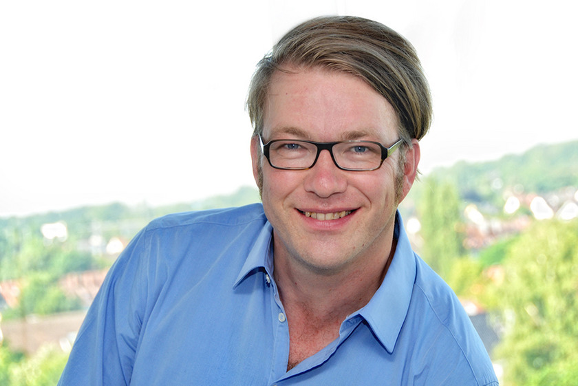 Auf dem Bild sieht man einen Mann mit Sietenscheitel und Brille.