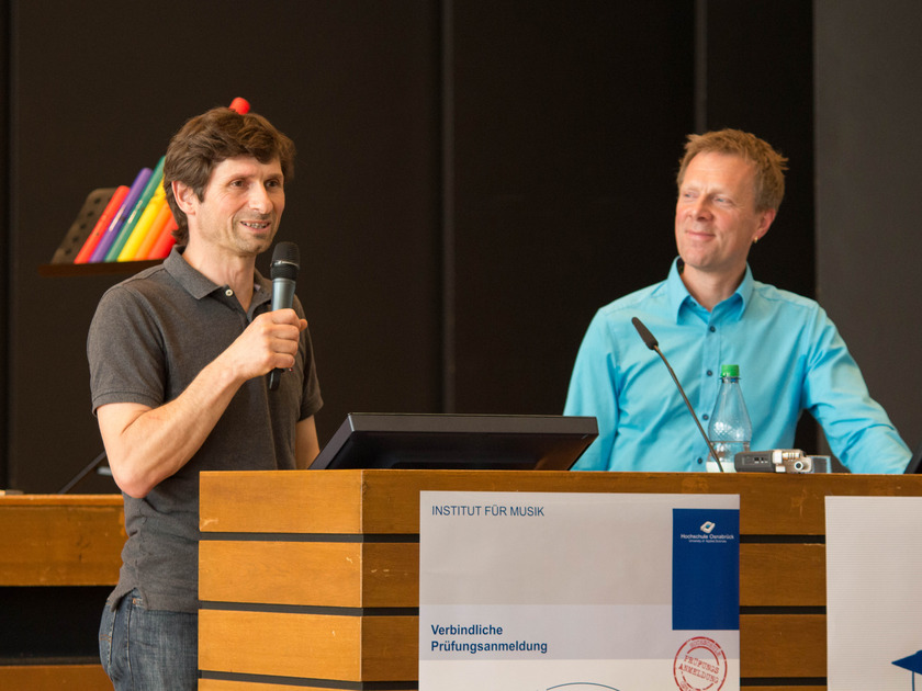 Man sieht zwei Männer am Rednerpult.