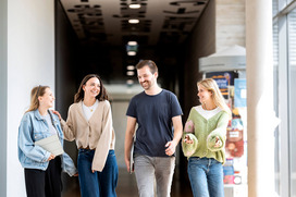 Vier Studierende gehen gemeinsam lachend durch das CN-Gebäude am Campus Caprivi.