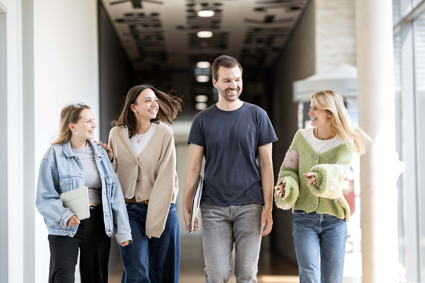 Vier Studierende gehen gemeinsam einen Flur entlang und unterhalten sich.