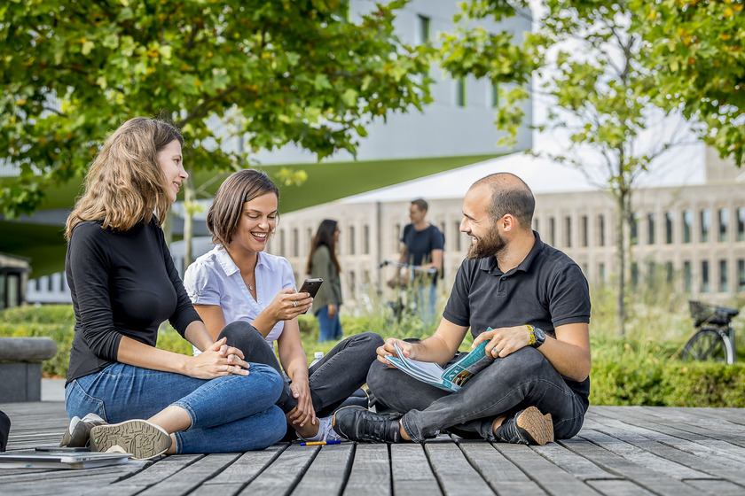 Studierende der Hochschule Osnabrück sitzen draußen vor dem SL Gebäude am Campus Westerberg
