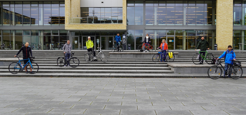 Personen mit Fahrrädern vor Mensagebäude