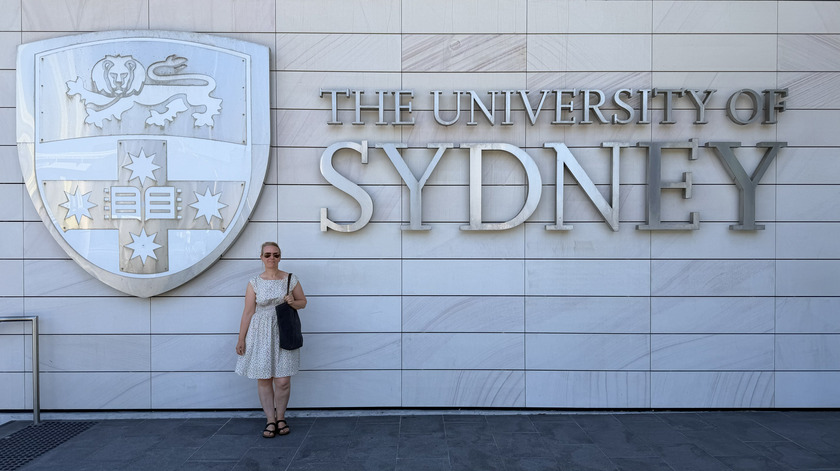 Frau steht vor dem Schil der University of Sydney. 