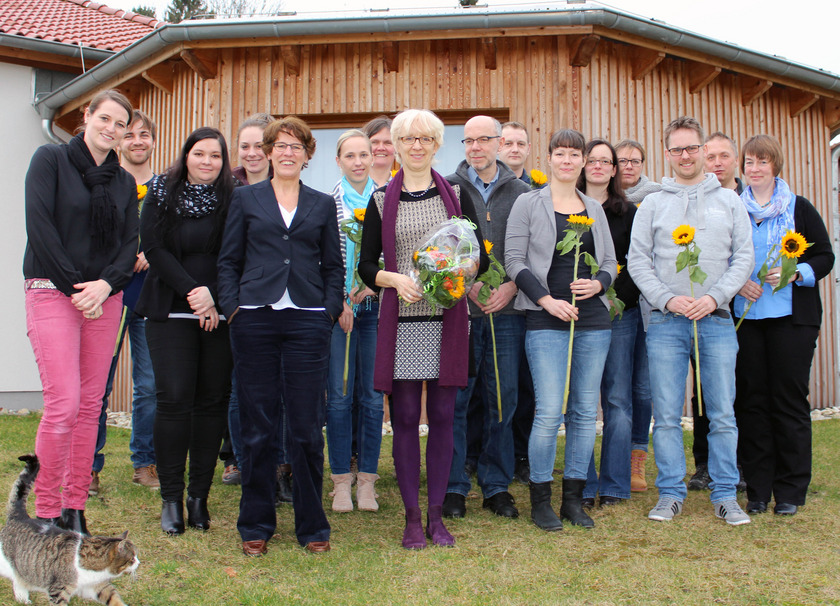 Man sieht eine Gruppe von Personen mit Sonnenblumen in der Hand.