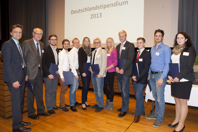 Eine Gruppe von zwälf Menschen steht mit Urkunden in der Hand nebeneinander.
