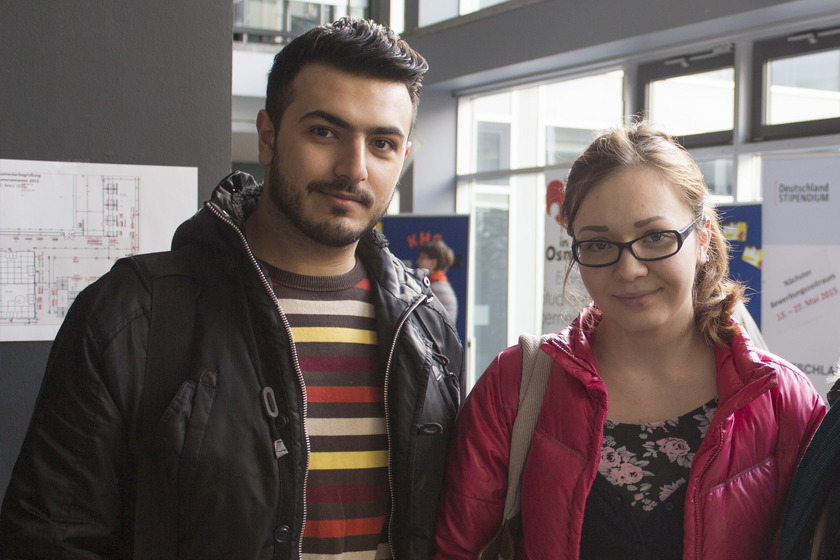 Ein junger Mann mit dunklen Haaren und eine junge Frau mit Brille und roter Jacke.