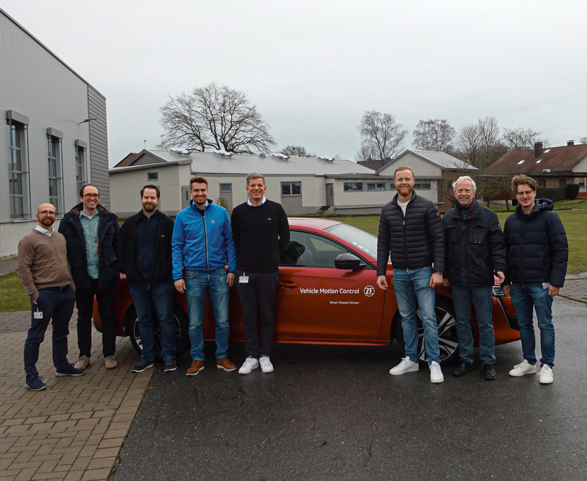 Gruppenfoto vor einem roten Testfahrzeug